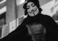 A black and white photo of a person wearing anonymous mask