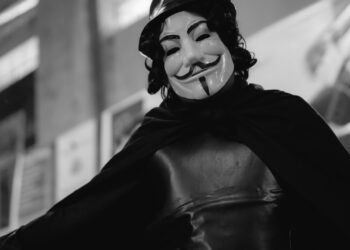 A black and white photo of a person wearing anonymous mask