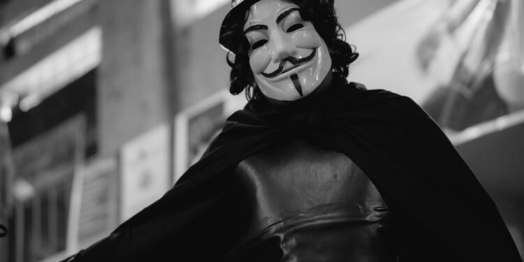 A black and white photo of a person wearing anonymous mask