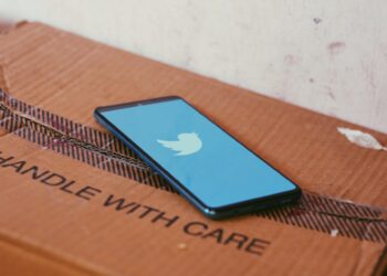 A phone placed on a card board box with Twitter app's Splash screen logo
