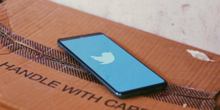 A phone placed on a card board box with Twitter app's Splash screen logo
