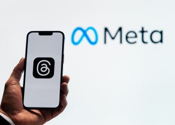 Threads app with Meta logo behind the phone