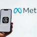 Threads app with Meta logo behind the phone